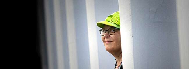 Leukemiasta parantunut Kirsi Kilponen ulkona katsomassa pylvään takaa.