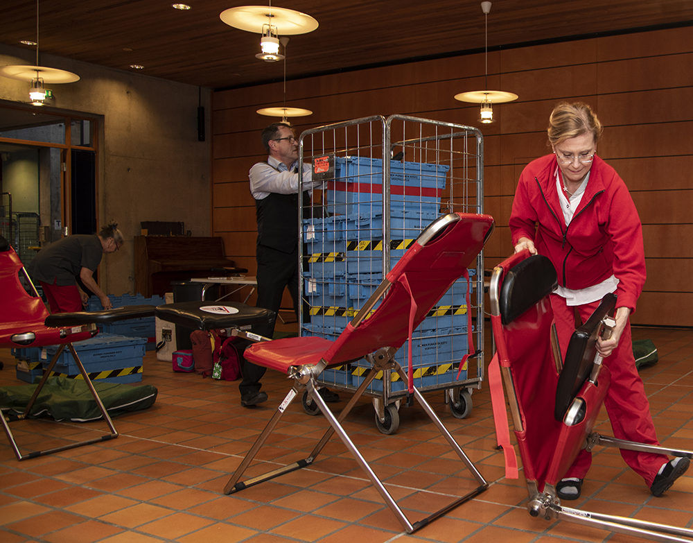 Kaksi henkilö pystyttää verenluovutustilaisuutta.