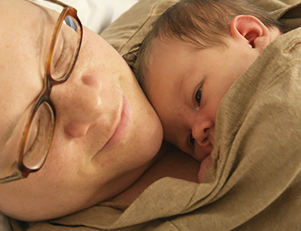 Nainen pitää sylissään pientä vauvaa, lähikuva kasvoista.