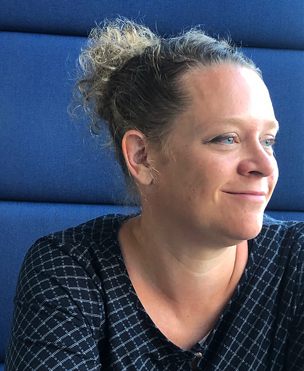 Nainen hymyilee ja katsoo hieman sivuun kamerasta.