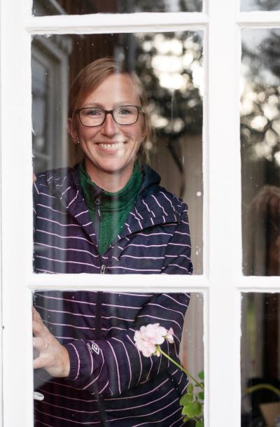 Nainen katsomassa ikkunan läpi kameraan.