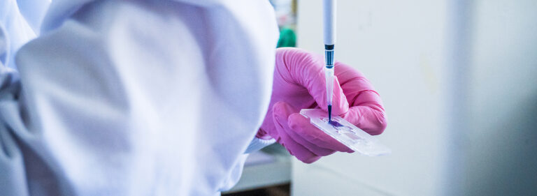A researcher's hands are pipetting a biobank sample.