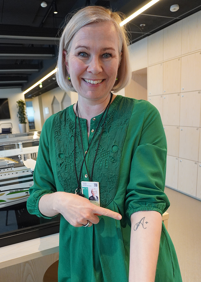 An employee shows their arm, where there is a blood group tattoo.