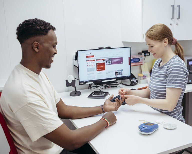 Veripalvelun hoitaja mittaa hemoglobiinin verenluovuttajan sormenpäästä.