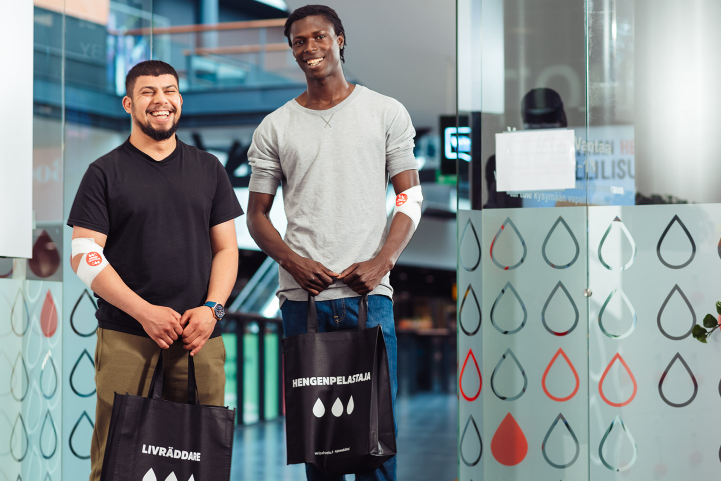 Kaksi verenluovuttajaa Hengenpelastaja-kassien kanssa.