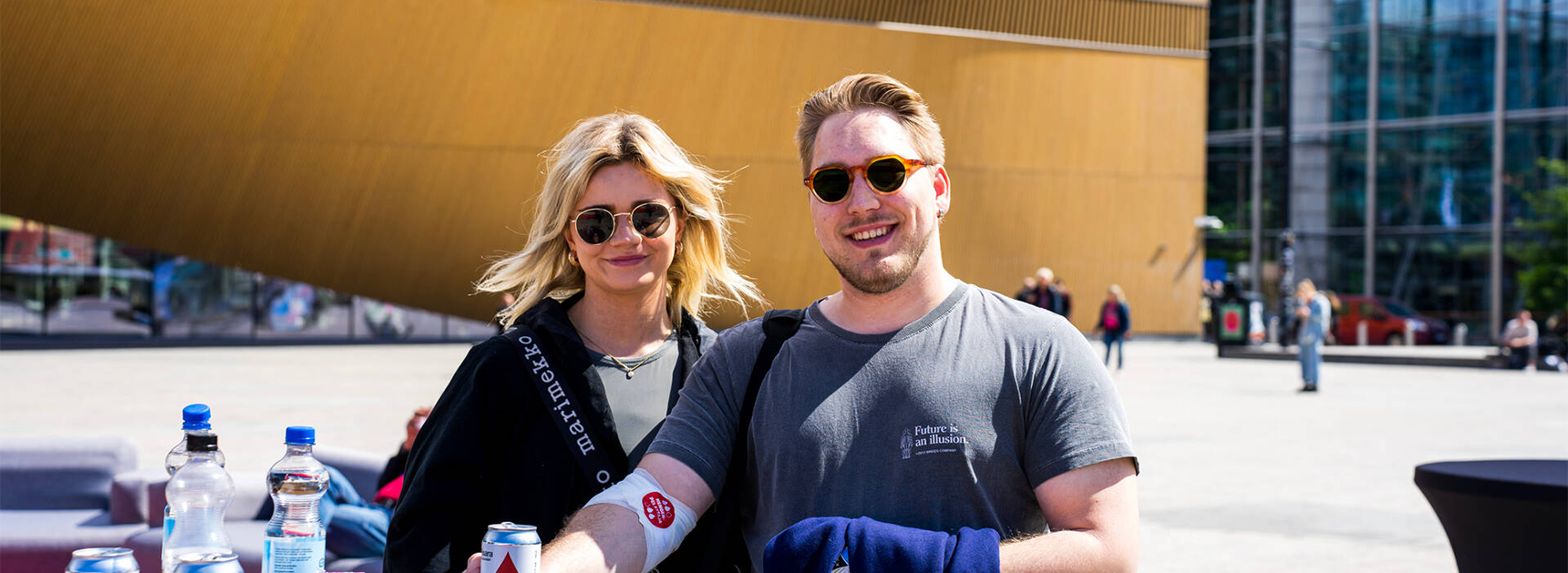 Kaksi hymyilevää henkilöä kuvattuna ulkona Veripalvelun kesätapahtumassa Maailman verenluovuttajien päivänä.