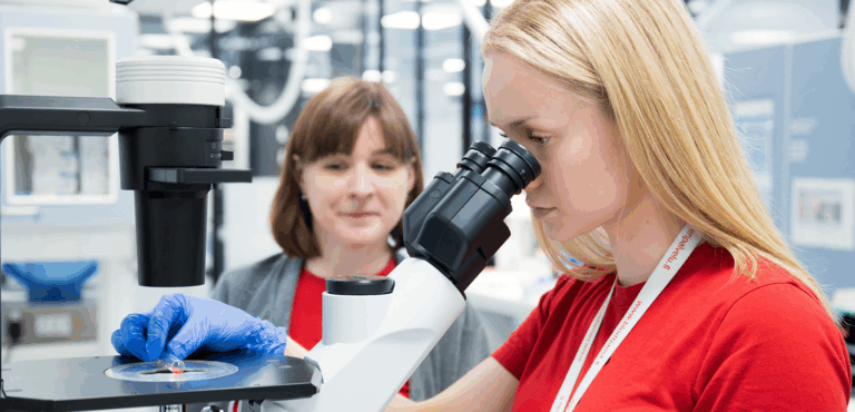 Veripalvelun laboratoriotyöntekijät mikroskoopin äärellä.