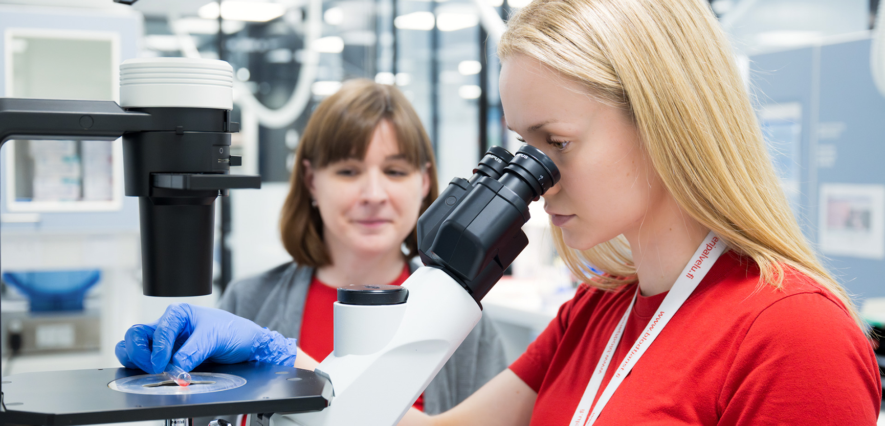 Veripalvelun laboratoriotyöntekijät mikroskoopin äärellä.