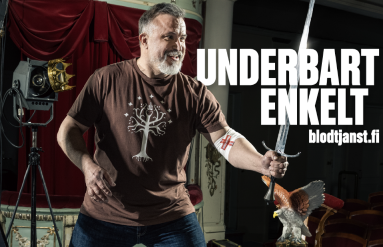 Kristo Salminen fäktas på scenen och har ett blodgivningsband på armbågen. På bilden står texten: Underbart enkelt, blodtjänst.fi.