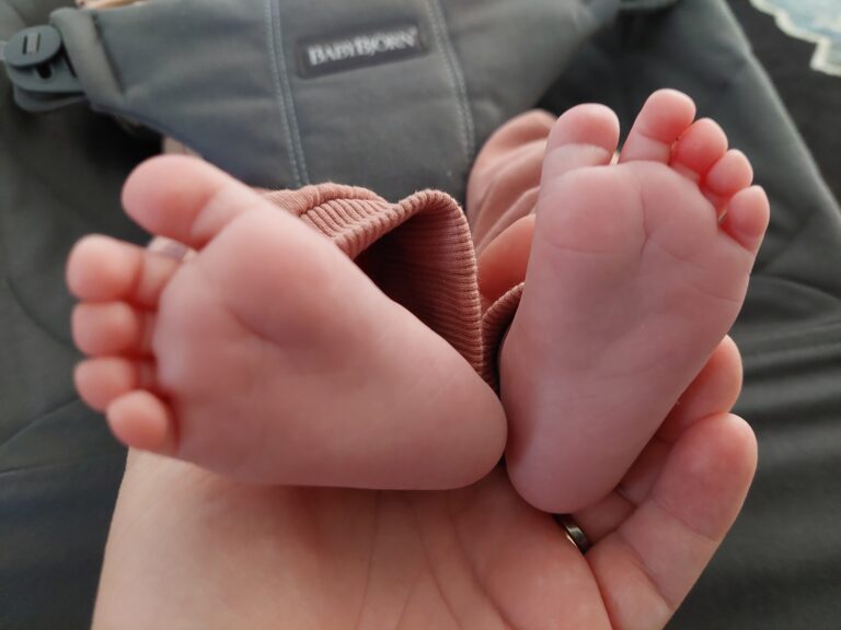 Henkilö pitää kädessään pieniä vauvan jalkoja.