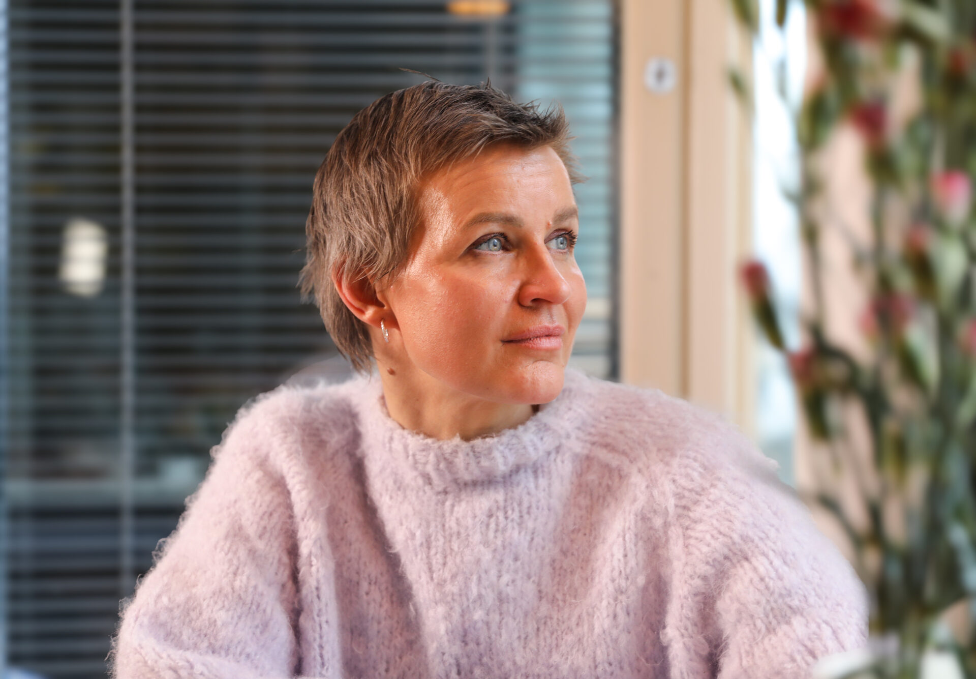 Milla Madetoja istuu pöydän äärellä ja katsoo ikkunasta ulos.